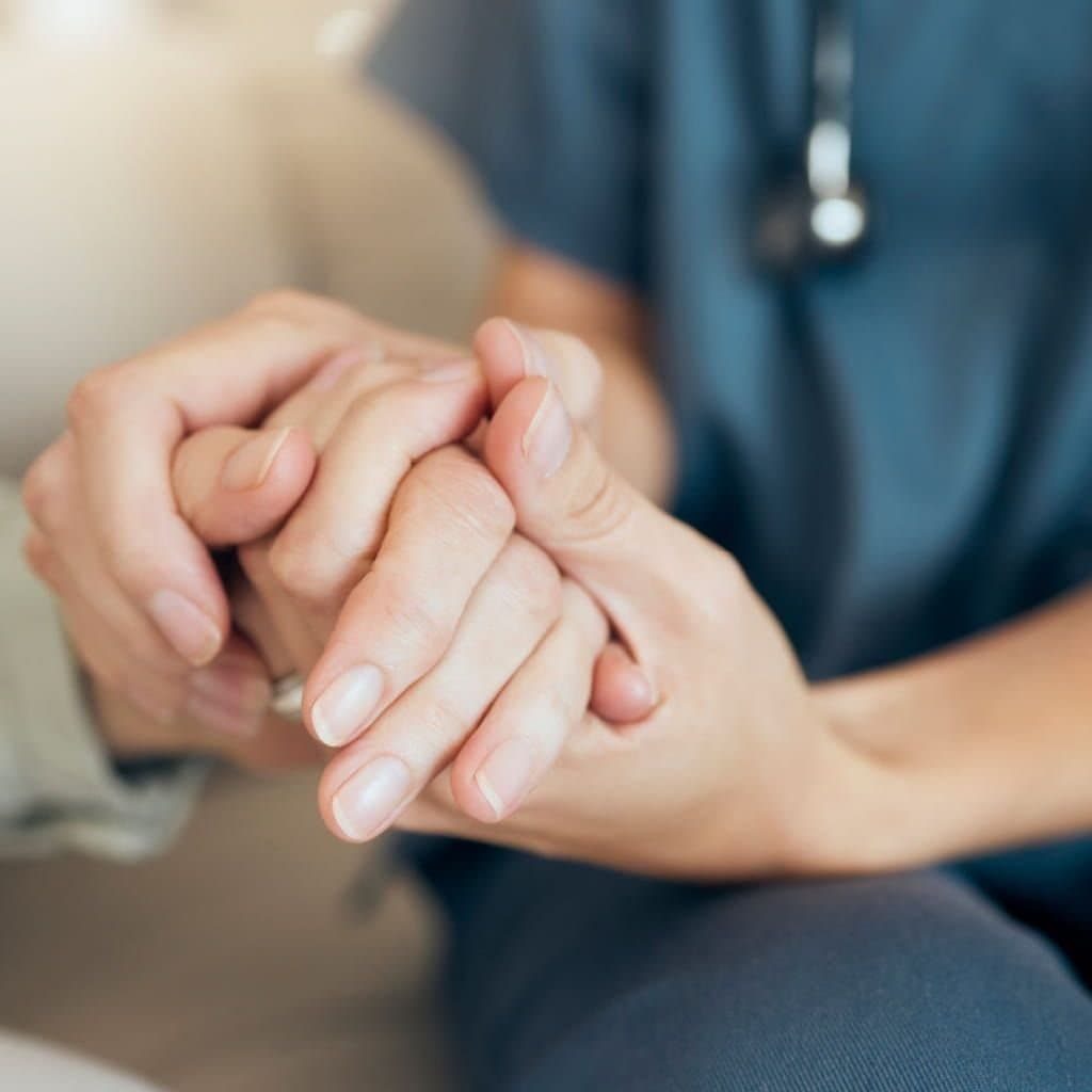 A clinician gently holding a patient's hands in reassurance