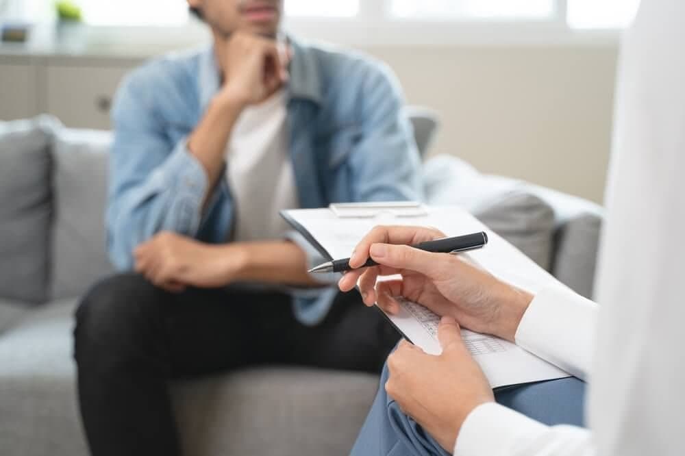Man talking with a clinician who takes notes during a counseling session