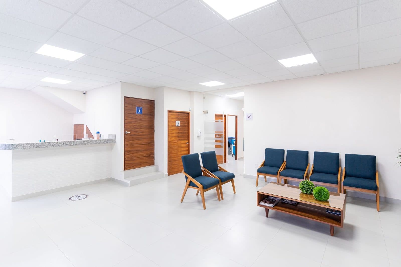 Bright, empty medical waiting room with blue chairs