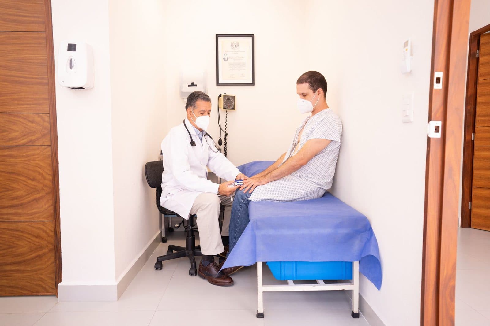 Physician checking a seated patient on an exam table in a clinic exam room