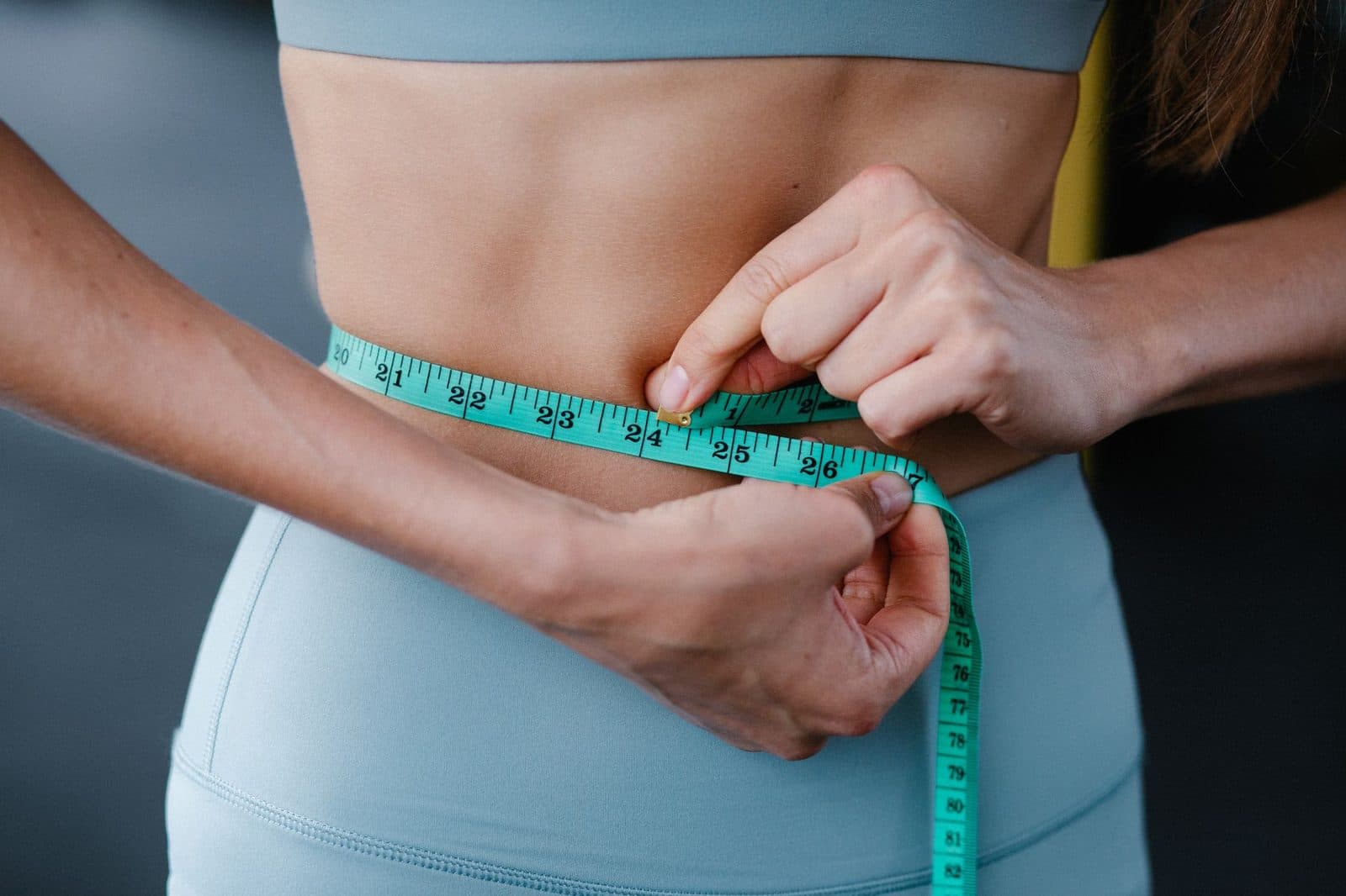 Woman measuring her waist with a tape measure