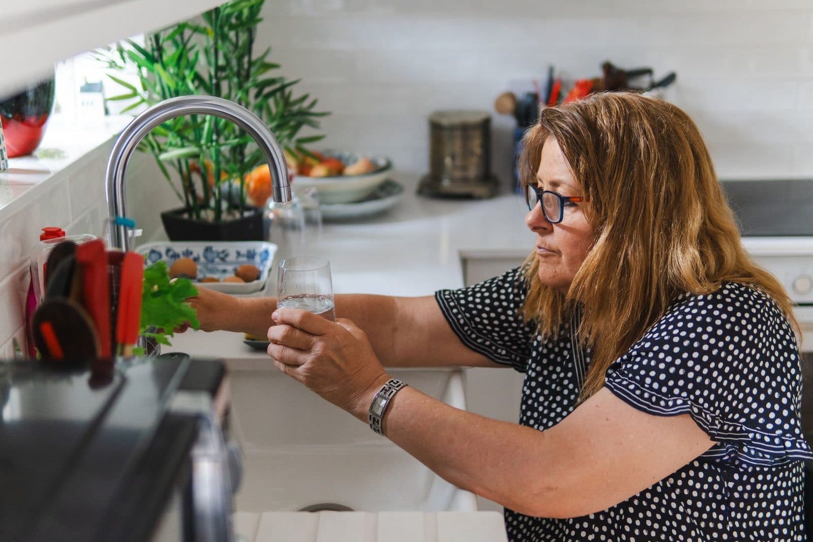 Woman filling a glass with water at the kitchen sink