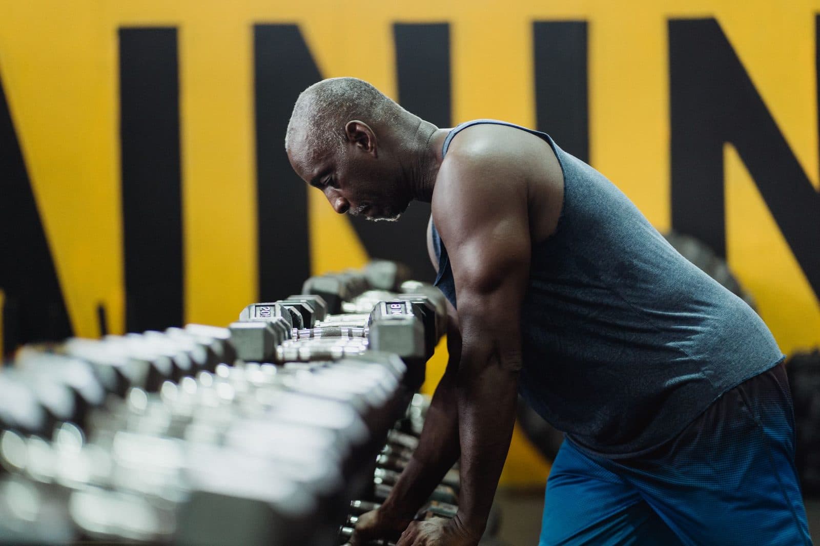 Mature man choosing a dumbbell from the rack during a strength workout