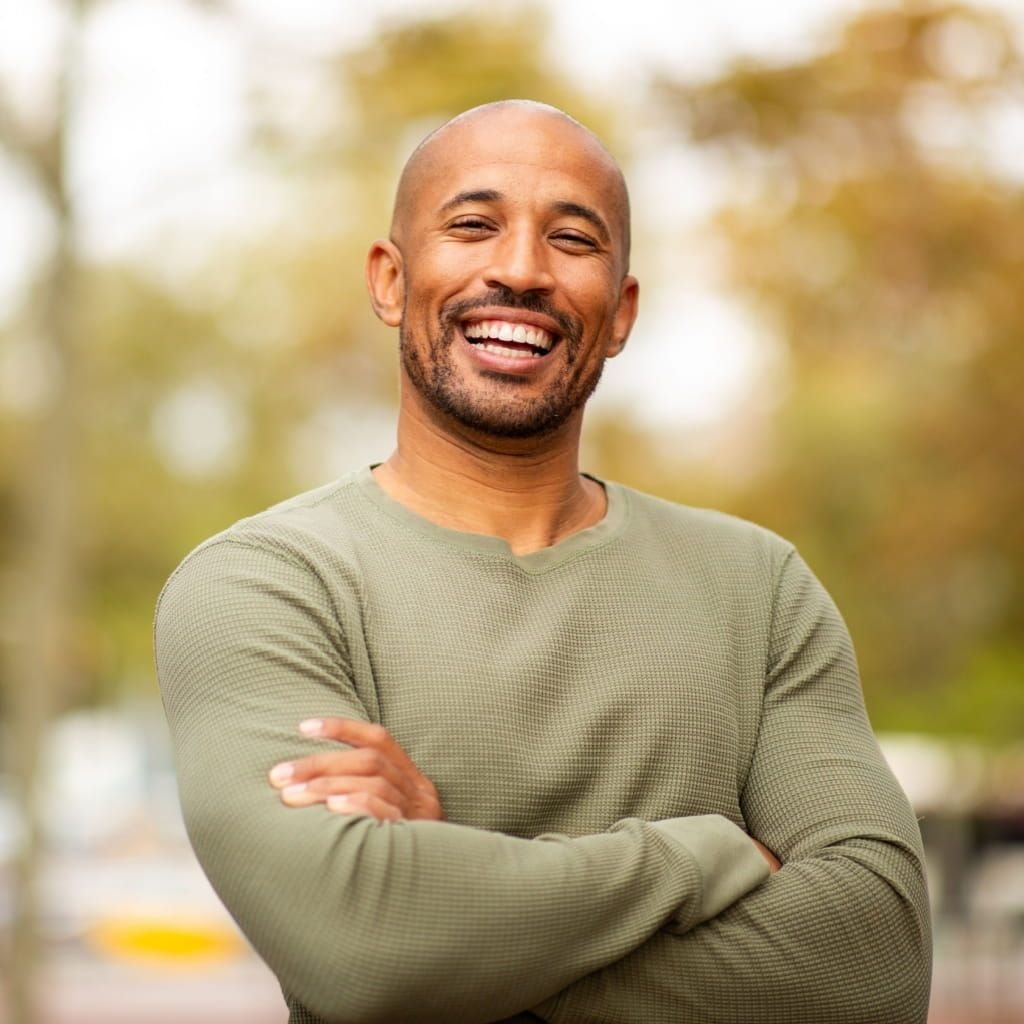 Smiling middle-aged man outdoors with his arms crossed