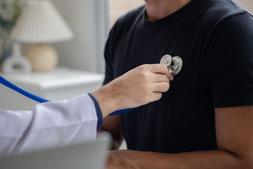 Physician listening to a patient's chest with a stethoscope during a checkup