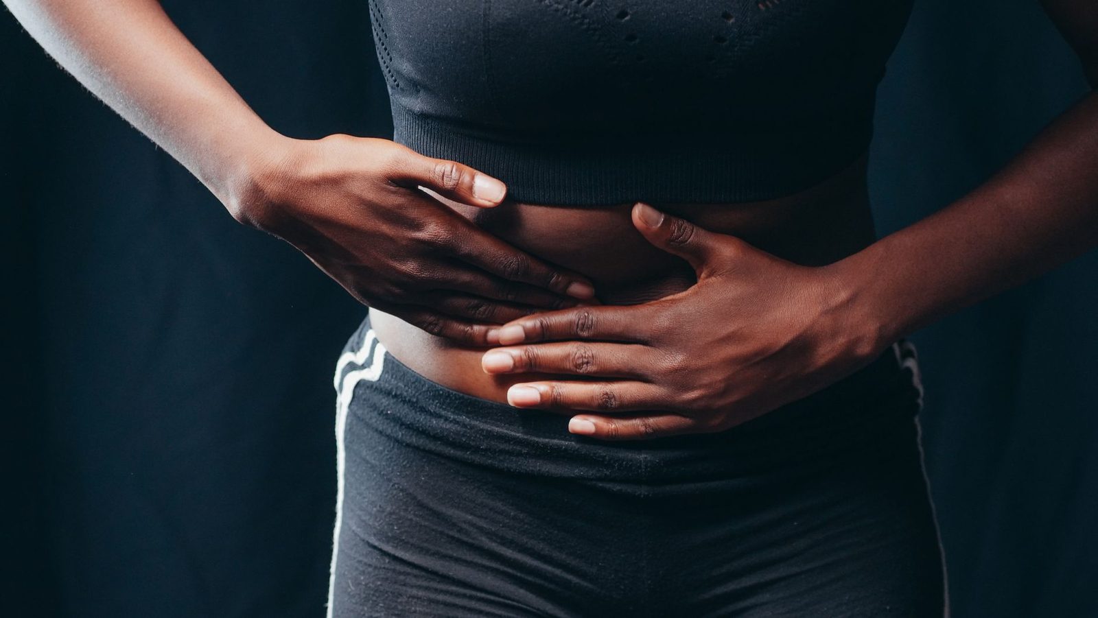 Person pressing both hands on the abdomen in discomfort