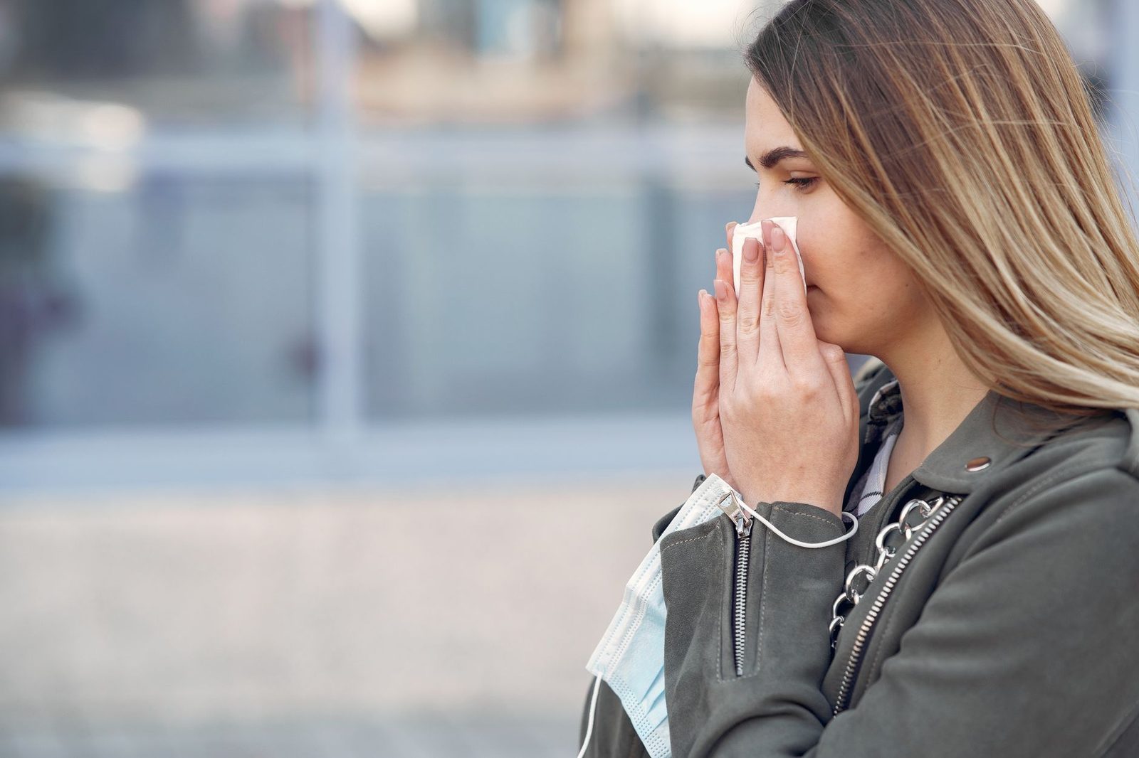 Woman sneezing into a tissue outdoors