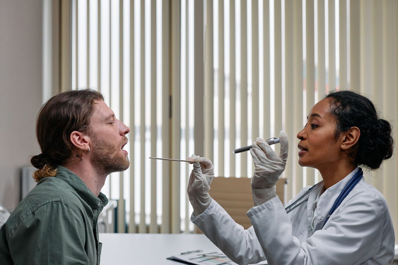 Physician examining a man's throat with a tongue depressor